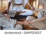 Healthy mindful women group sitting in circle meditating together holding hands doing yoga breathing exercises giving support during body health retreat holistic healing training session. Close up.