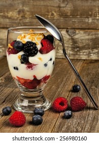 Healthy Mixed Berry, Granola And Yogurt Parfait On Wood Background With Spoon