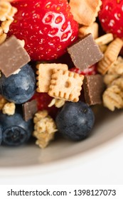 Healthy Muesli Or Cereal Breakfast Bowl With Granola Made Of Toasted Rolled Oats, Organic Honey, Milk Chocolate Chips And Tiny Graham Cracker Cookies Served With Fresh Strawberries And Blueberries