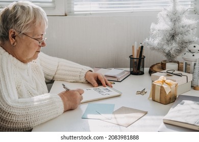 Healthy New Years Resolutions For Older Adults. Senior Mature Old Woman In White Sweater Writing Handwritten Text My Goals In Open Notepad On The Table. Planning And Setting Goals