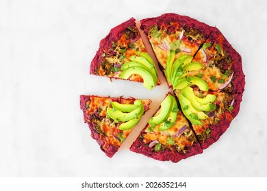 Healthy, No Carb Beet Crust Pizza With Avocados, Pesto Sauce And Onions. Overhead View With Cut Slices On A White Marble Background.