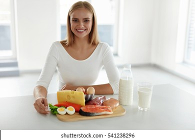Healthy Nutrition. Beautiful Smiling Woman Sitting At Table With Different Raw Food Products And Ingredients. Happy Girl With High-Protein Foods, Meat, Fish, Dairy Products In Kitchen. High Resolution