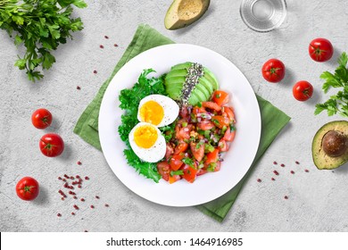 Healthy Nutritious Paleo Keto Breakfast - Kale With Boiled Egg, Fresh Cherry Tomato Salsa And Avocado With Chia And Hemp Seeds On White Plate On Light Background. Flat Lay.