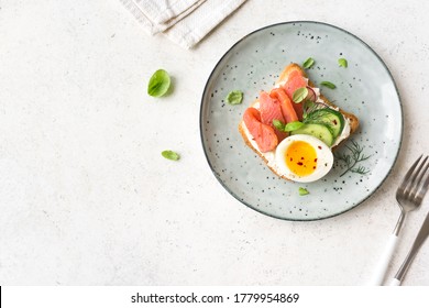 Healthy open salmon sandwich with cream cheese, soft egg, veggies and greens. Delicious protein fish sandwich for breakfast or brunch, top view, copy space.
