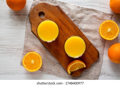 Healthy Orange Juice on a rustic board on a white wooden surface, top view. Flat lay, from above, overhead. 