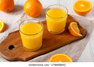 Healthy Orange Juice on a rustic board on a white wooden background, side view. 