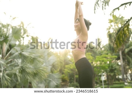 healthy outdoor lifestyle fit young Asian woman 30s in pink sportswear engages in yoga and stretches muscles in public park at sunrise. concept of wellness and well being with fitness yoga girl.