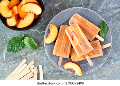 Healthy Peach Yogurt Ice Pops On A Plate, Top View Table Scene Against A Dark Stone Background