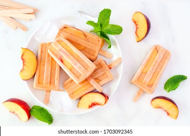 Healthy Peach Yogurt Ice Pops On A Plate, Overhead View Table Scene With A White Marble Background