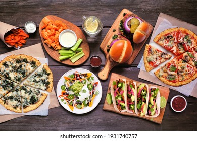 Healthy Plant Based Fast Food Table Scene. Top Down View On A Wood Background. Cauliflower Crust Pizzas, Bean Burgers, Mushroom Tacos, Bell Pepper Nachos And Cauliflower Wings And Sweet Potato Fries.