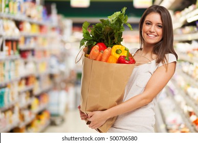 Healthy positive happy woman holding a paper shopping bag full of fruit and vegetables - Powered by Shutterstock