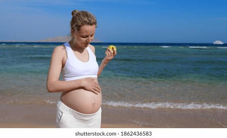 Healthy Pre Natal Nutrition During Family Holidays. Sporty Pregnant Woman Eating Apple By Sea Enjoying Happy Lifestyle 