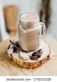 Healthy Protein Shake With Banana, Peanut Butter, Oats And Agave Syrup In A Stylish Glass, Decorated With Chocolate Protein, Oatmeal And Mint On A Wooden Plate, Brown, Beige, Bright