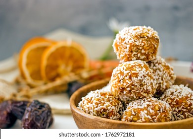 Healthy raw energy balls. Candy vegan balls of dates, coconut pulp, carrots in a wooden bowl are laid out in the shape of a pyramid. Top view, concept of useful home-made candies without sugar