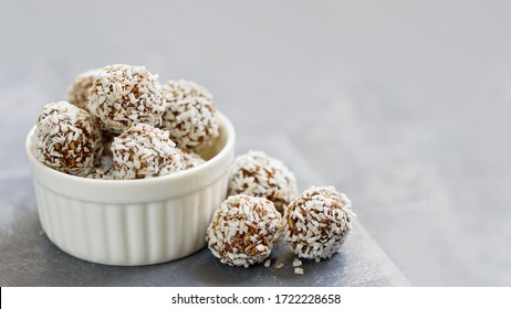 Healthy raw energy balls with cocoa, coconut, sesame, chia on white background. Healthy homemade paleo chocolate energy balls with rolled oats, nuts, dates. Raw vegan healthy dessert, selective focus
