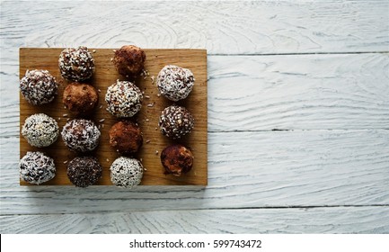 Healthy raw energy balls with cocoa, coconut, sesame, chia on a white textured wooden background.  Vegan chocolate truffles. Copy space