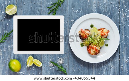 Healthy restaurant food. Seafood dish top view with copy space at tablet. Menu, cooking site, recipe template. Ratatoille with cheese and shrimp top view, flat lay with copyspace at blue rustic wood.