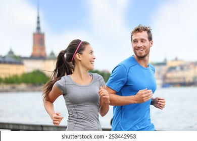 Healthy runners running in Stockholm city cityscape background. Riddarholmskyrkan church in the background, Sweden, Europe. Healthy multiracial young adults, asian woman, caucasian man.