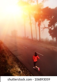 Healthy Running Runner Woman Early Morning Sunrise Workout On Misty Mountain Road Workout Jog. Sun Flare Through The Mist Gives Atmospheric Feel And Depth To This Set Of Fitness Images