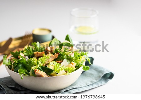 Healthy salad bowl with  different  lettuce, chicken, cheese and croutons  on the table in reataurant. 