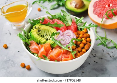 Healthy salad bowl with salmon, grapefruit, spicy chickpeas, avocado, red onion and arugula. Delicious balanced food concept