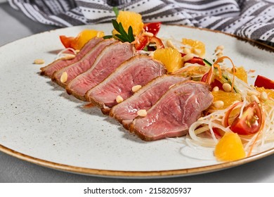 Healthy salad with duck meat, orange and vegetables. Chinese food - duck salad with citrus and fresh dressing. Sliced duck meat with crispy vegetables and pine nuts