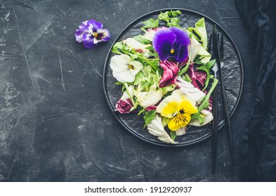 Healthy Salad With Green And Purple Lettuce And Edible Flowers On Black Background. Spring Salad Mix With Edible Flowers. Top View. Copy Space.