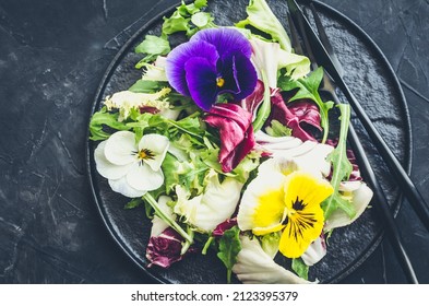 Healthy salad with green and purple lettuce and edible flowers on black background. Spring salad mix with edible flowers. Top view. - Shutterstock ID 2123395379