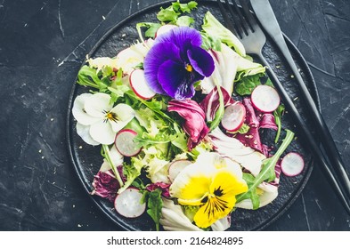 Healthy Salad With Green And Purple Lettuce And Edible Flowers On Black Background. Spring Salad Mix With Edible Flowers. Top View.