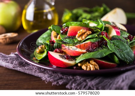 Healthy salad plate with apple, dried cranberry, walnut, spinach and poppy seed dressing on wooden background close up. Healthy food. Clean eating.