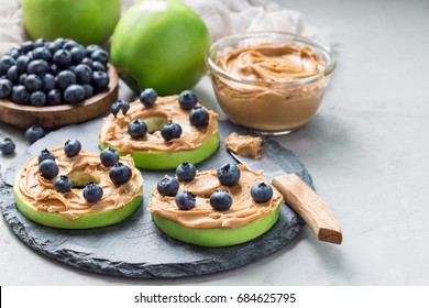 Healthy sandwich. Green apple rounds with peanut butter and blueberries on slate board, horizontal, copy space