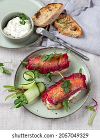 Healthy Sandwiches With Sourdough Crisp Bread Slices, Sour Cream, Beetroot Cured Salmon And Cucumber On Green Ceramic Plate, Top View

A