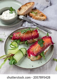 Healthy sandwiches with sourdough crisp bread slices, sour cream, beetroot cured salmon and cucumber on green ceramic plate, top view

A - Shutterstock ID 2057895428