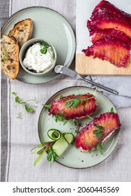 Healthy Sandwiches With Sourdough Crisp Bread Slices, Sour Cream, Beetroot Cured Salmon And Cucumber On Green Ceramic Plate, Top View

A