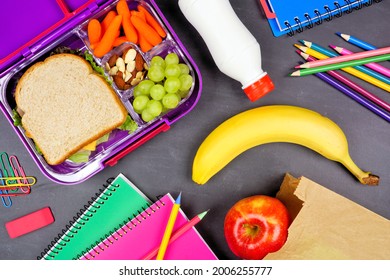 Healthy School Lunch Box And School Supplies. Overhead View On A Chalkboard Background.