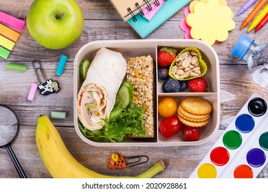 Healthy School Lunch Box And School Supplies On Wooden Table. Top View