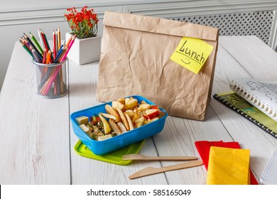 Healthy School Lunch For Child Or Teenager. Craft Paper Package, Pile Of Exercise Books, Water, Bag And Food In Lunch Box On White Wood Table, Cracker With Cheese, Nuts, Oatmeal Porridge And Apples