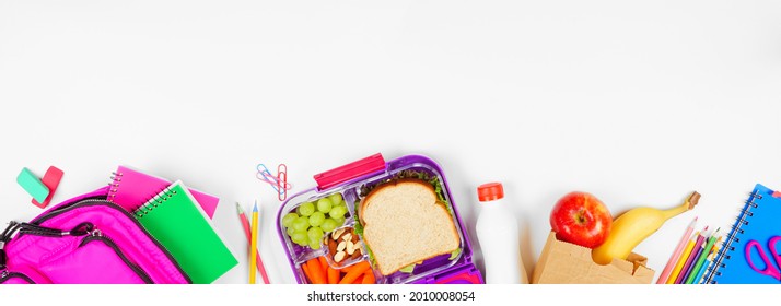 Healthy school lunch with school supplies. Top view bottom border on a white banner background. Back to School concept.