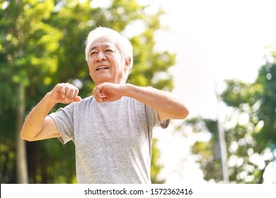 Healthy Senior Asian Man Walking Exercising Stretching Arms Outdoors