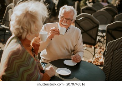 Healthy senior couple drinking coffee in the outdoor cafe on a sunny autumn day - Powered by Shutterstock