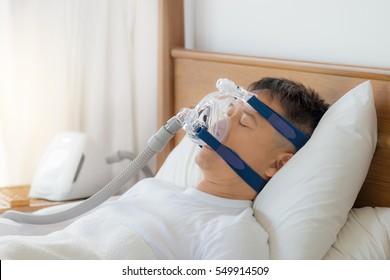 Healthy senior man wearing cpap mask sleeping smoothly on his back pillow high without snoring  ,side view .Obstructive sleep apnea therapy.

