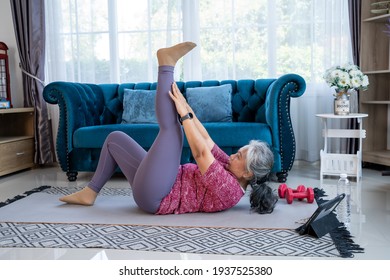 Healthy Senior Woman Doing Exercise Stretching Legs With Lying Leg Lift, Workout Fitness Pose At Home