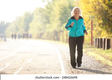 Healthy Senior  Woman Jogging at the Pedestrian Walkway in the Bright Autumn Evening