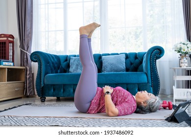 Healthy Senior Woman Lie On The Floor And Raise Two Leg Up While Doing Exercise Stretching Legs With Lying Leg Lift, Workout Fitness Pose At Home