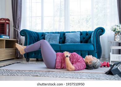 Healthy Senior Woman Lie On The Floor And Raise Two Leg Up While Doing Exercise Stretching Legs With Lying Leg Lift, Workout Fitness Pose At Home