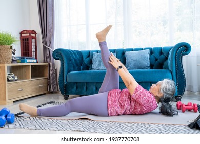 Healthy Senior Woman Lie On The Floor And Lift Up Body While Doing Exercise Stretching Legs With Lying Leg Lift, Workout Fitness Pose At Home