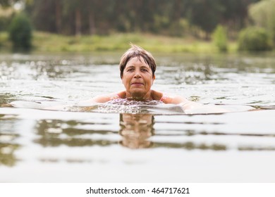 Healthy Senior Woman Swimming In The Lake Or River. Happy Elderly Lady Enjoying Active Summer Vacation. Sportive Lifestyle. Active Retirement Concept.