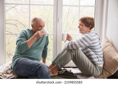 healthy seniors lifestyle. relaxing at home, Hygge. Slow life. Enjoying the little things. an elderly couple drinks tea and and communicate sitting near the window of the house - Powered by Shutterstock