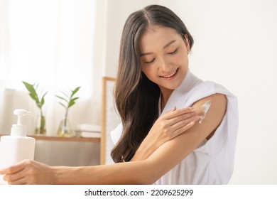 Healthy skin care, beauty asian young woman in bathrobe, towel after shower bath at home, hand in applying, putting moisturizer on her arm. Skin body cream moisturizing lotion, routine in the morning - Shutterstock ID 2209625299