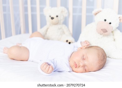 healthy sleep of a newborn baby in a crib in the bedroom with a soft toy bear on a cotton bed - Powered by Shutterstock